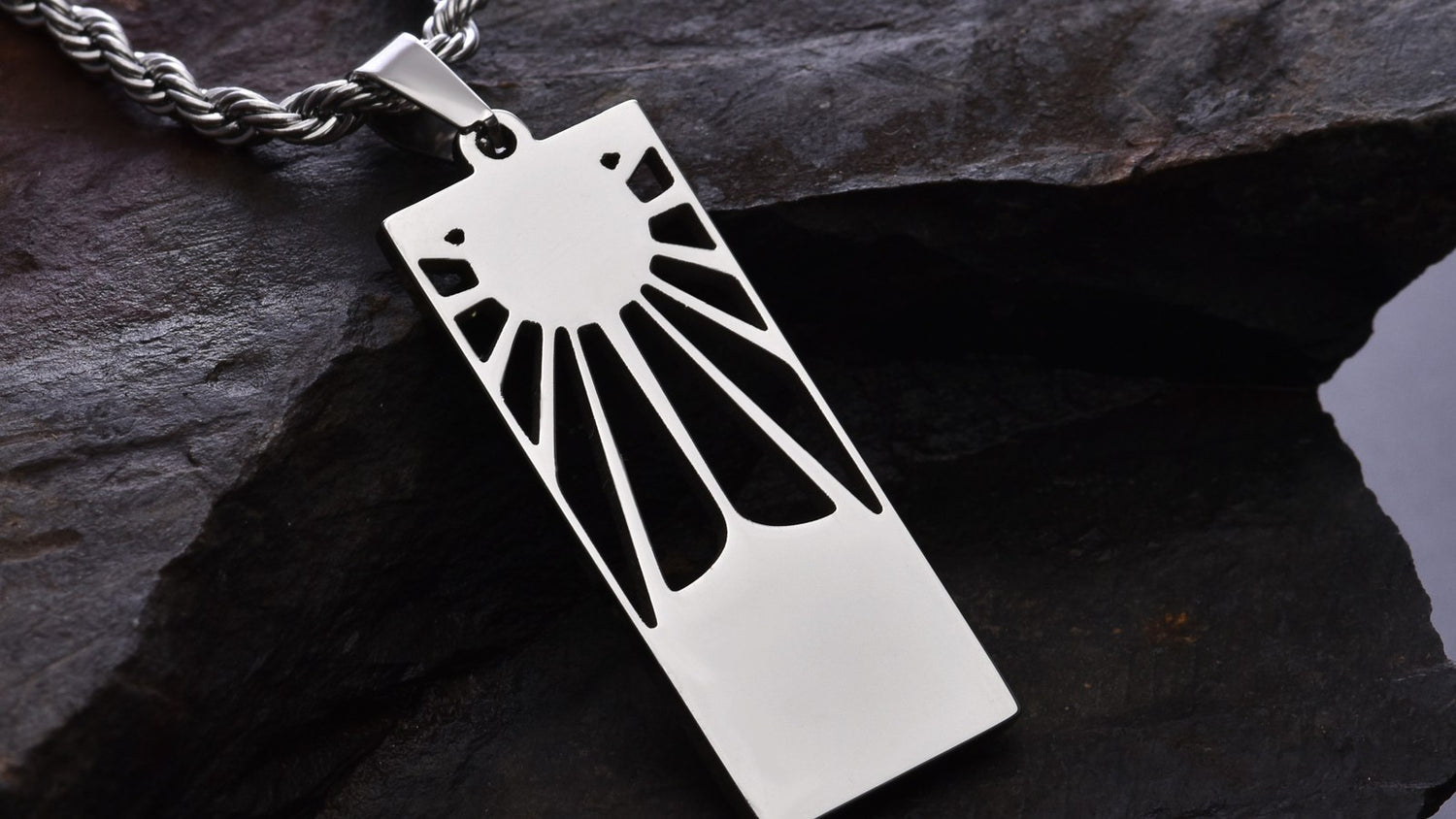 Demon Slayer titanium pendant on a chain, photographed on dark slate